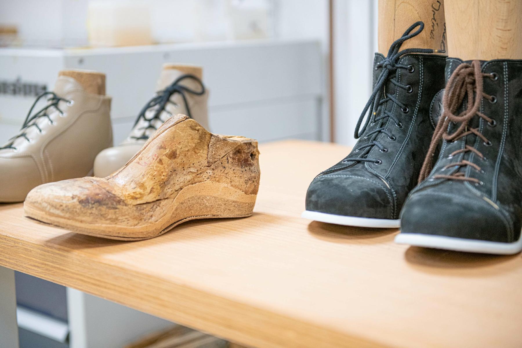 Auf dem Bild sind Schuhe und Leisten auf einem Tisch zu sehen.